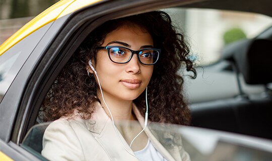 woman sitting in taxi listening to headphones